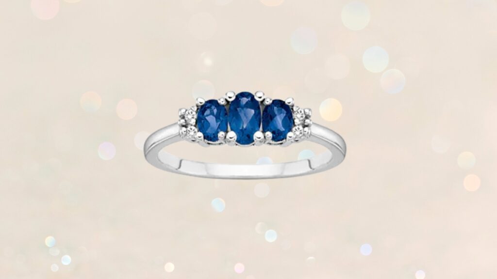 A white gold engagement ring with three oval blue sapphires accented by small round diamonds on each side.