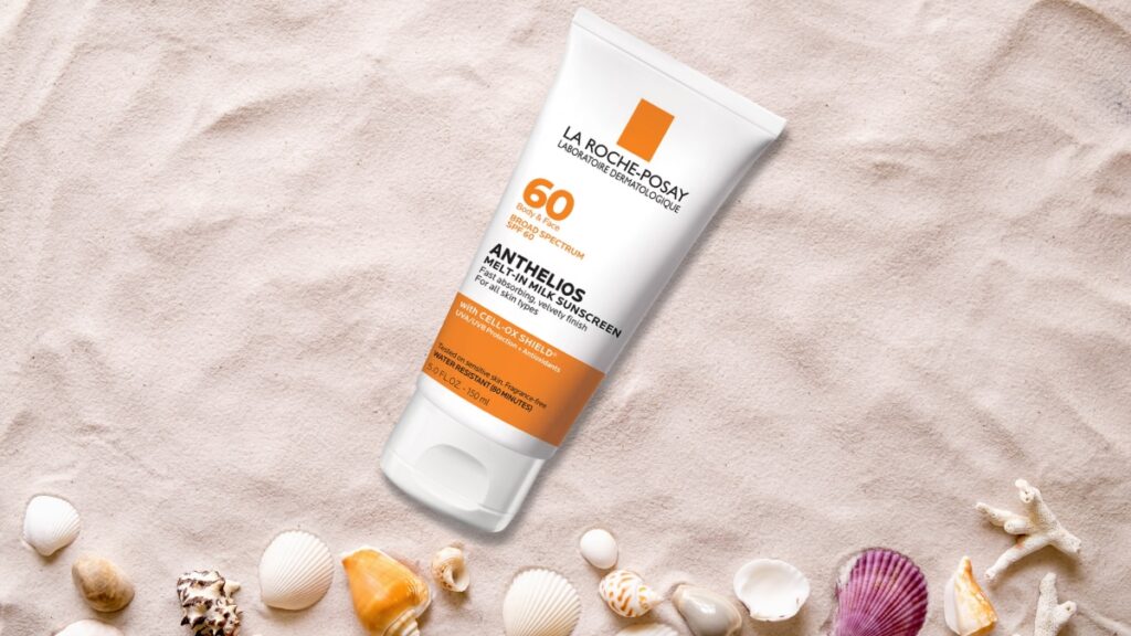 La Roche-Posay Anthelios Melt-In Milk SPF 60 sunscreen tube placed on sand with seashells, highlighting sun protection for face and body.